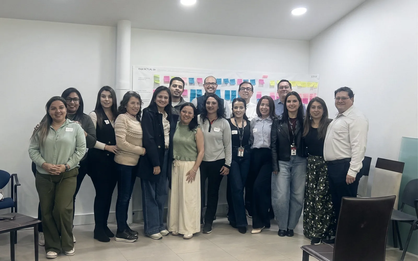 Equipo completo de una organización al término de una sesión de la Escuela de Habilidades Blandas CX, con el trabajo del taller aún en la pared.